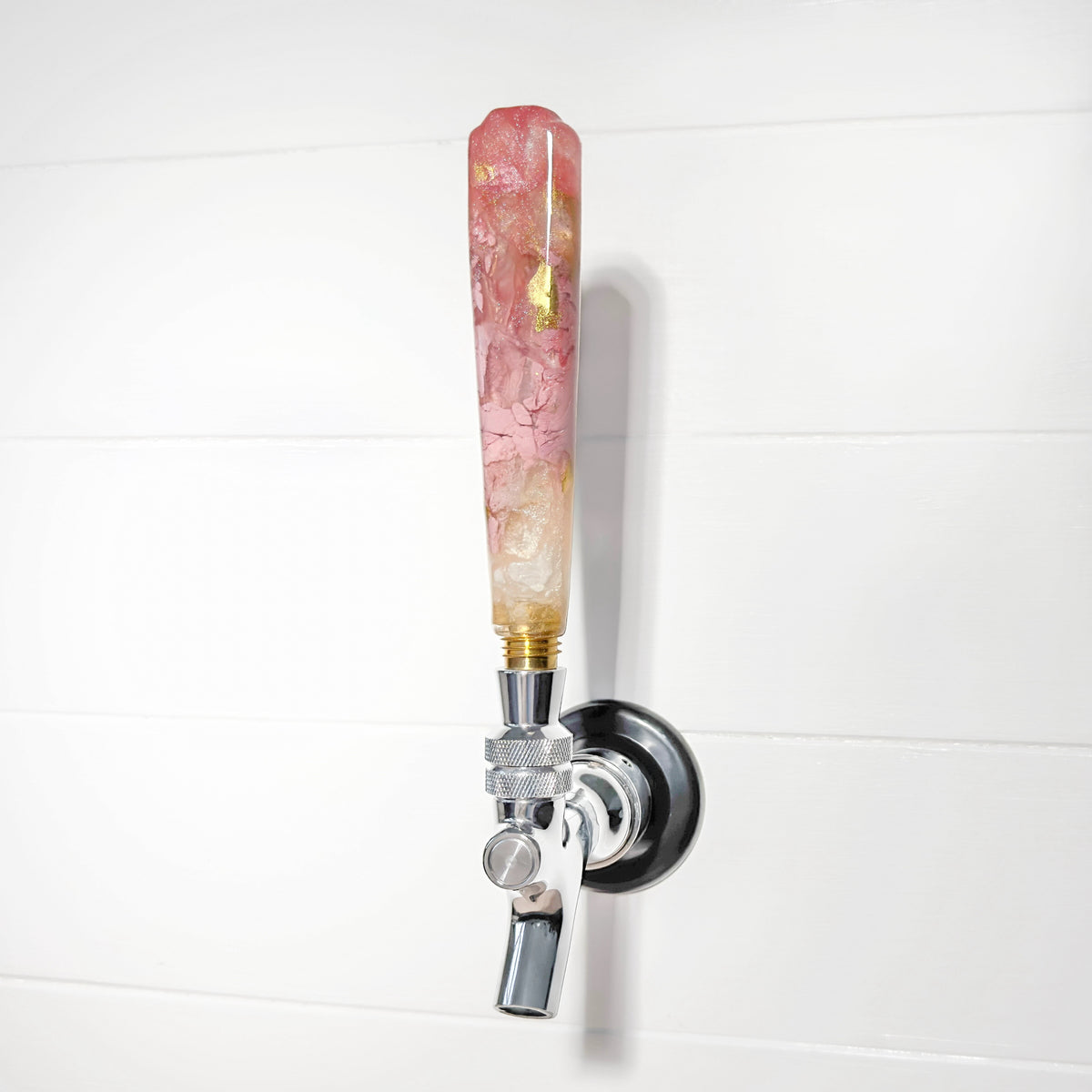 Decorative beer tap with a pink and gold handle on a white background