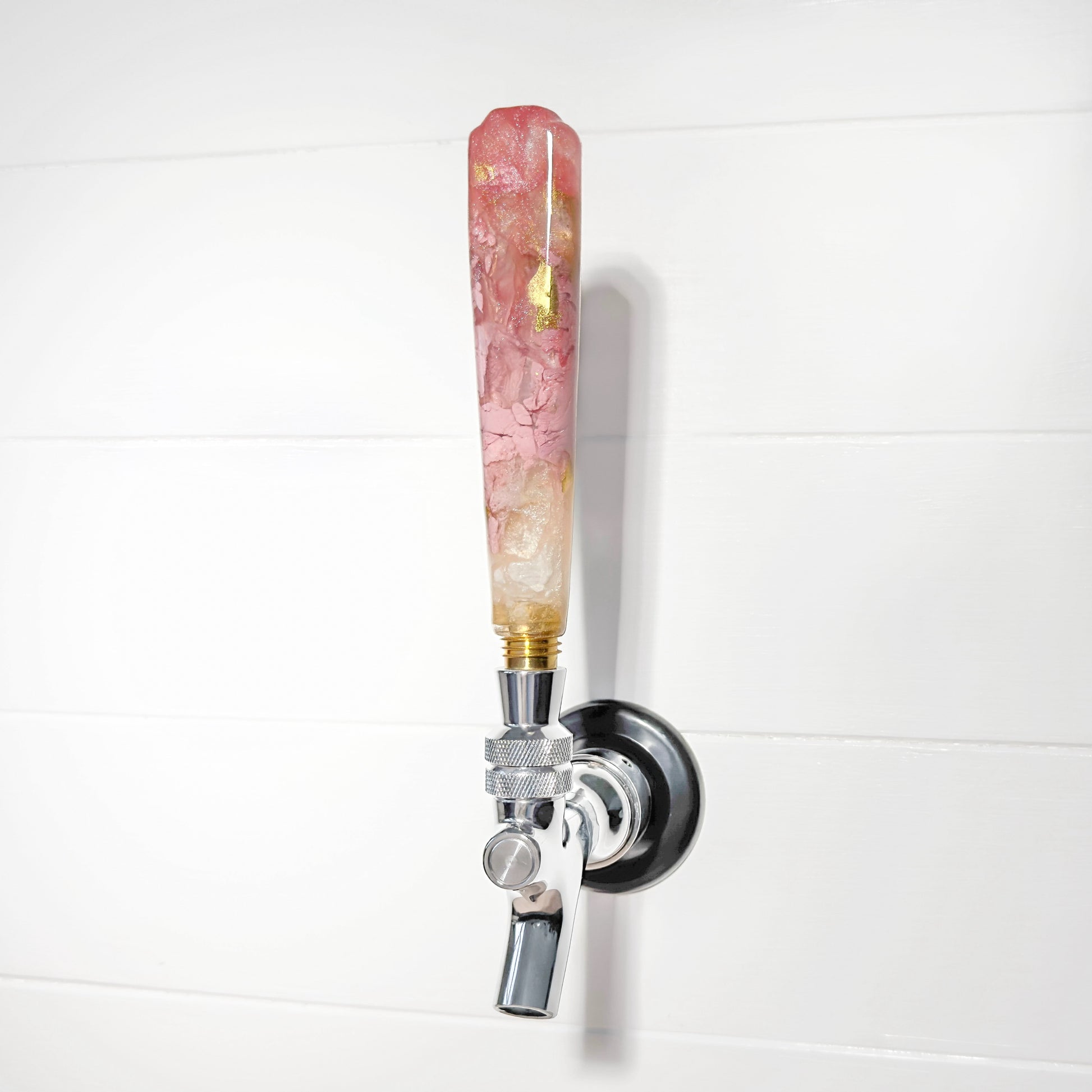 Decorative beer tap with a pink and gold handle on a white background