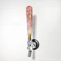 Decorative beer tap with a pink and gold handle on a white background