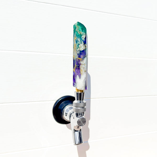 Decorative beer tap handle in purple and green with a white background